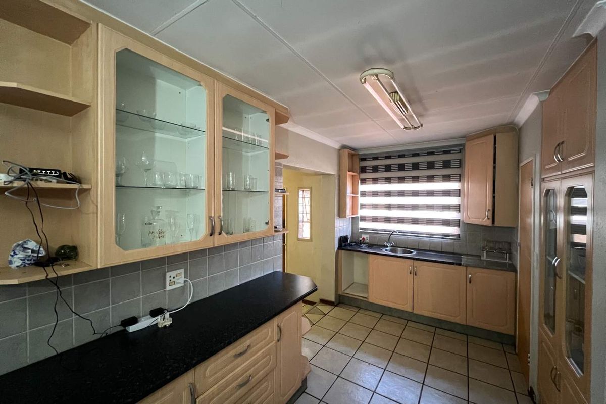 A functional kitchen featuring laminate cabinetry, granite countertops, ceramic tile flooring, and a stainless steel sink with a tiled backsplash.