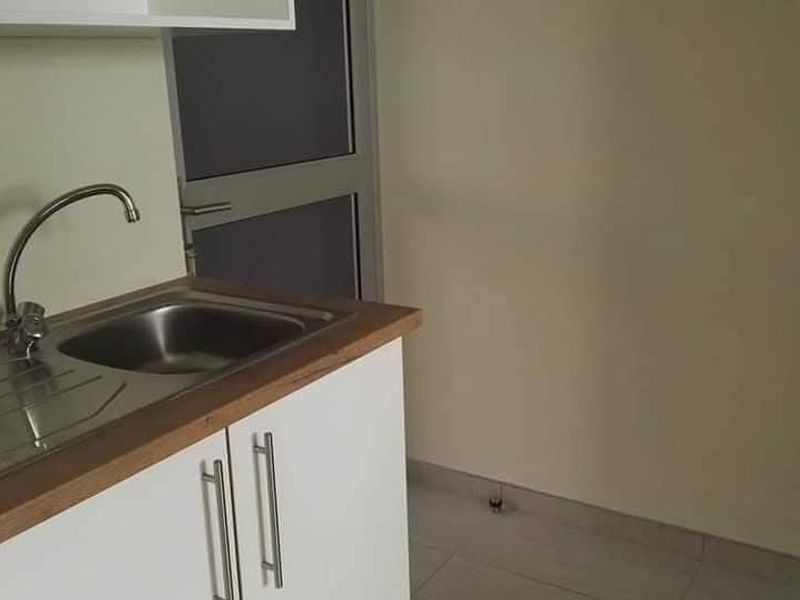 A compact kitchen area featuring a stainless steel sink, laminate countertop, and white base cabinetry with modern hardware.