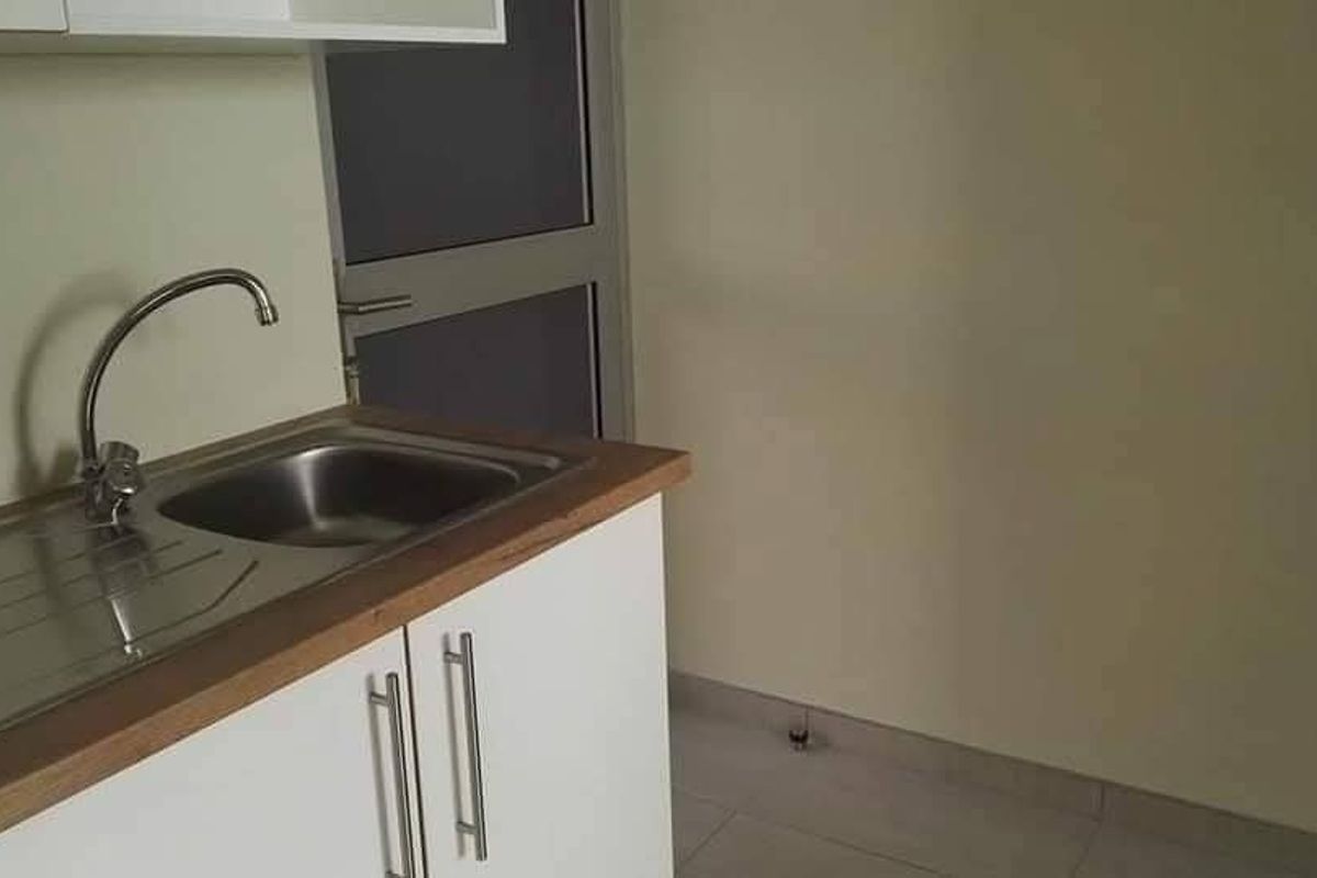 A compact kitchen area featuring a stainless steel sink, laminate countertop, and white base cabinetry with modern hardware.