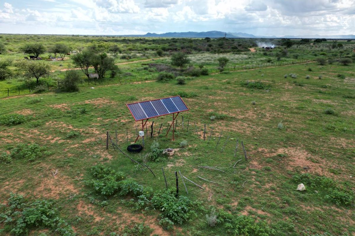 Aerial view of a rural farm property featuring a standalone solar panel array installation set within an open field.