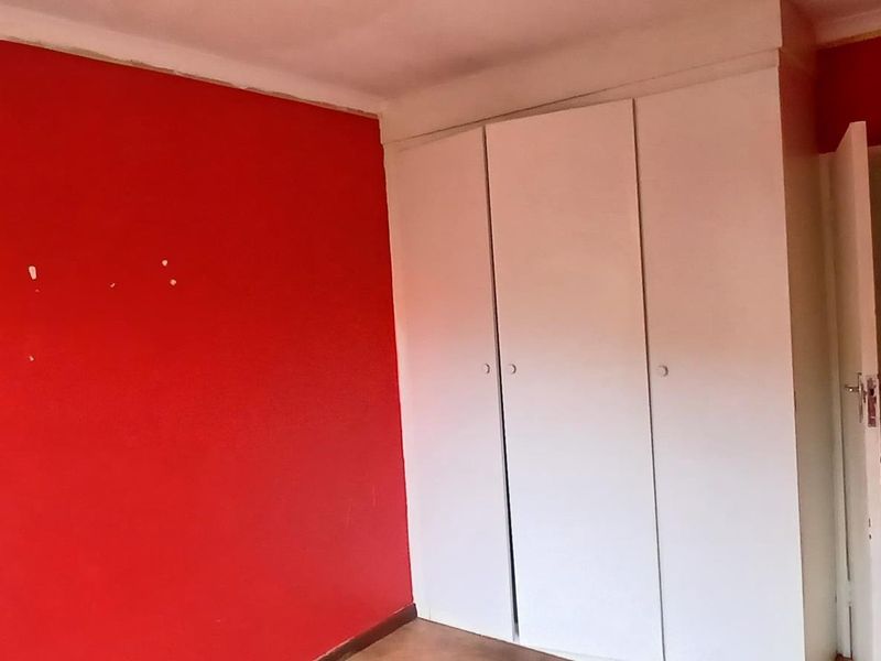 An empty bedroom featuring a built-in wardrobe and coving, requiring cosmetic updates to the wall finishes.