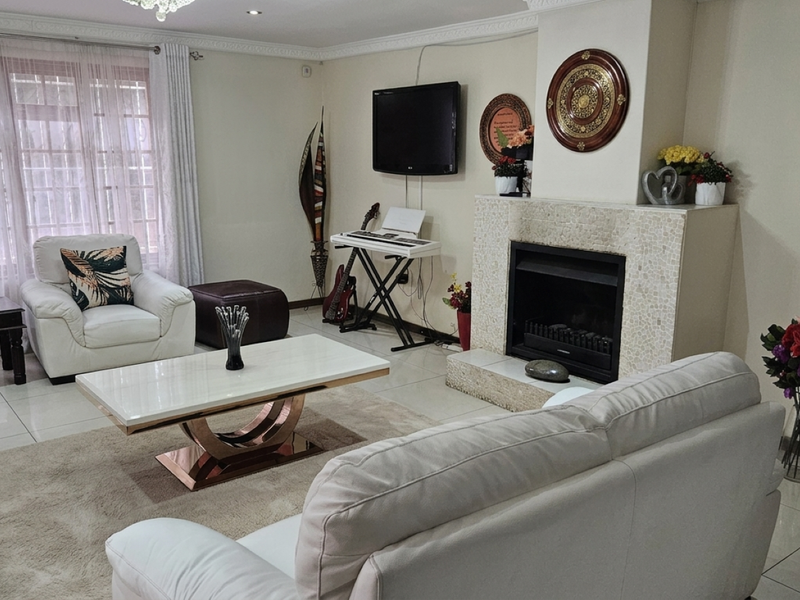 A comfortable living room featuring a tiled floor, decorative cornice, and a central fireplace with a mosaic-tiled surround.