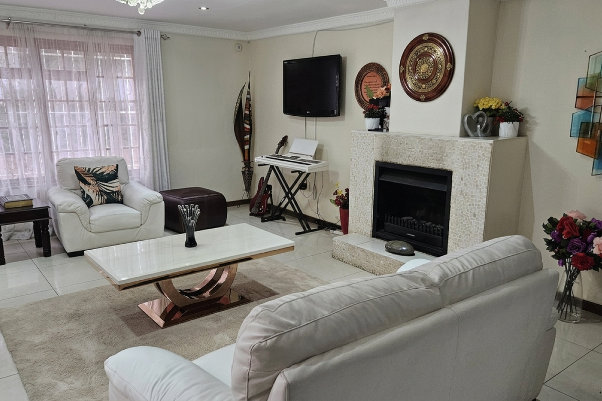 A comfortable living room featuring a tiled floor, decorative cornice, and a central fireplace with a mosaic-tiled surround.