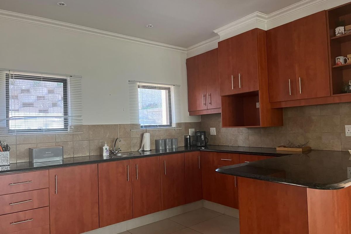 A functional kitchen featuring wooden cabinetry, granite countertops, tiled backsplash, and recessed lighting, offering a practical layout for daily meal preparation.