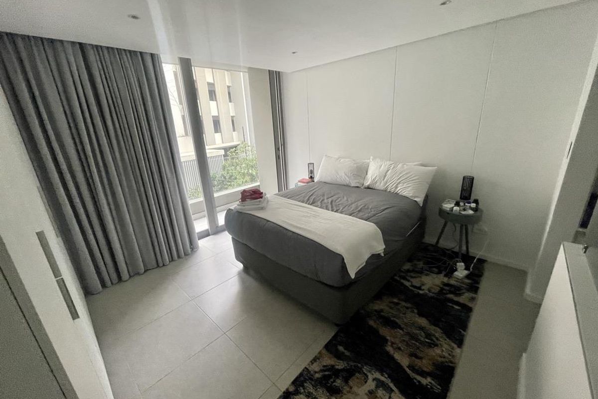 A modern bedroom featuring large floor-to-ceiling windows with full-length curtains, tiled flooring, and recessed ceiling lighting.