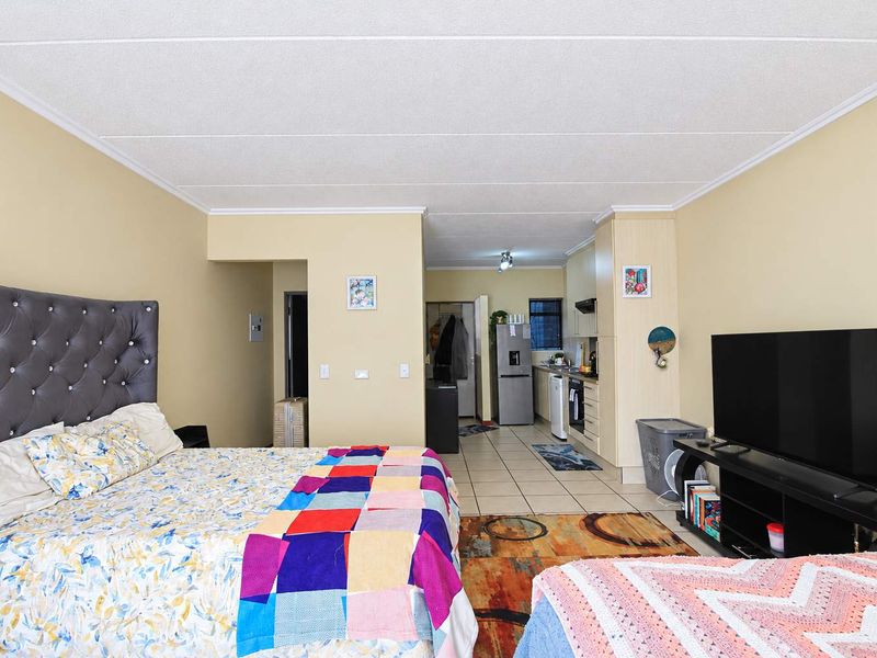 Open-plan studio apartment featuring a combined bedroom and kitchen area with tiled flooring and functional built-in cabinetry.