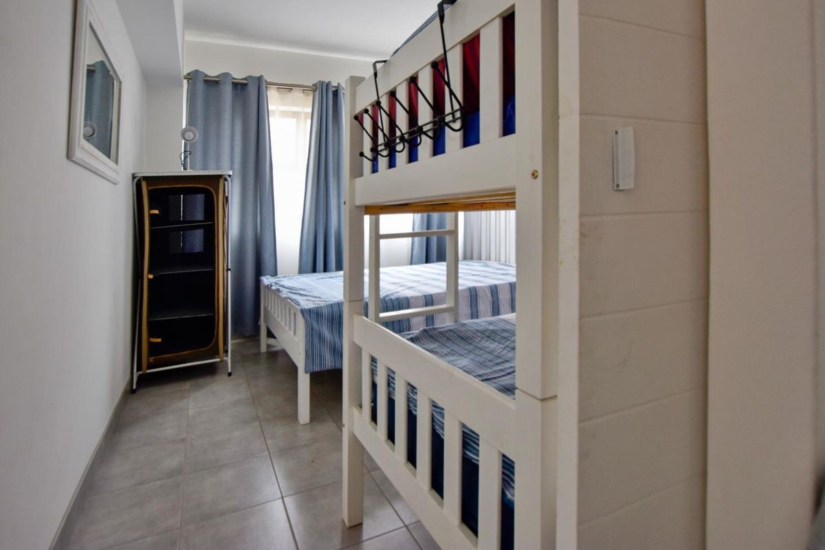 A bedroom featuring tiled flooring and neutral wall finishes, providing a functional space for sleeping arrangements.