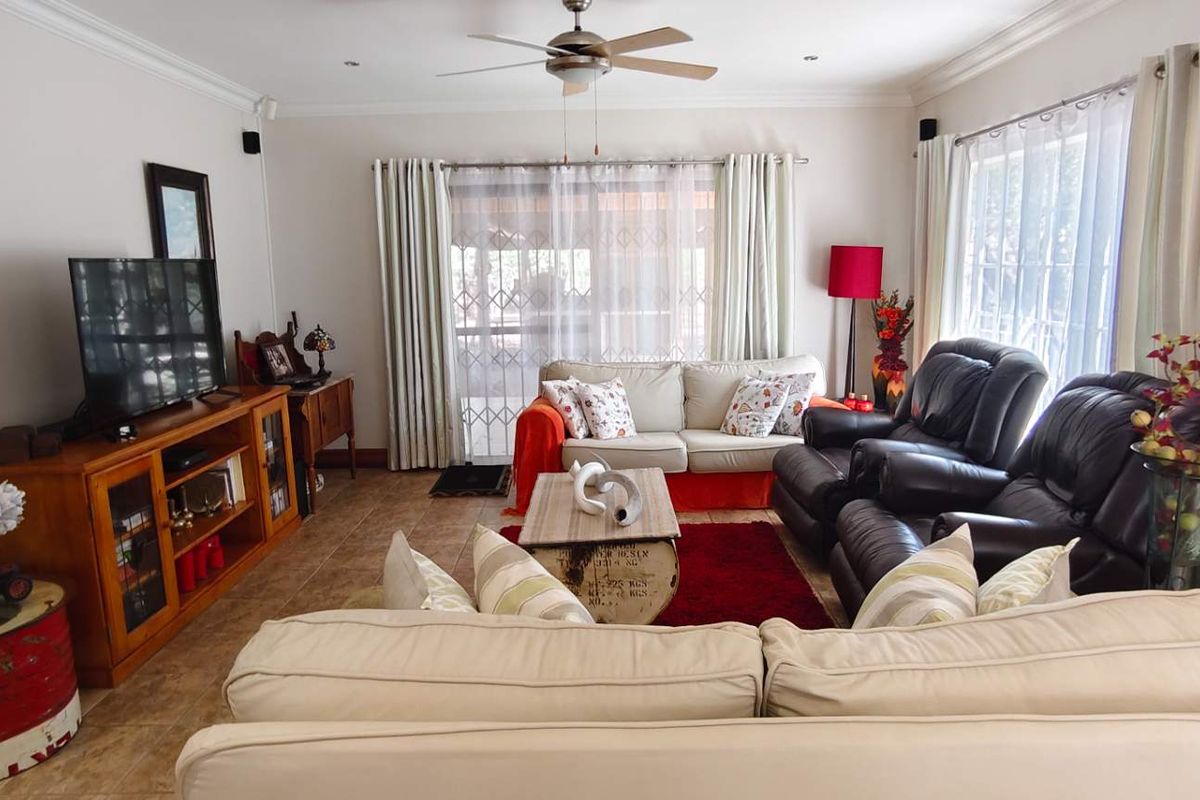 A comfortable living room featuring tiled flooring, a ceiling fan, and large sliding glass doors providing access to the outdoor area.