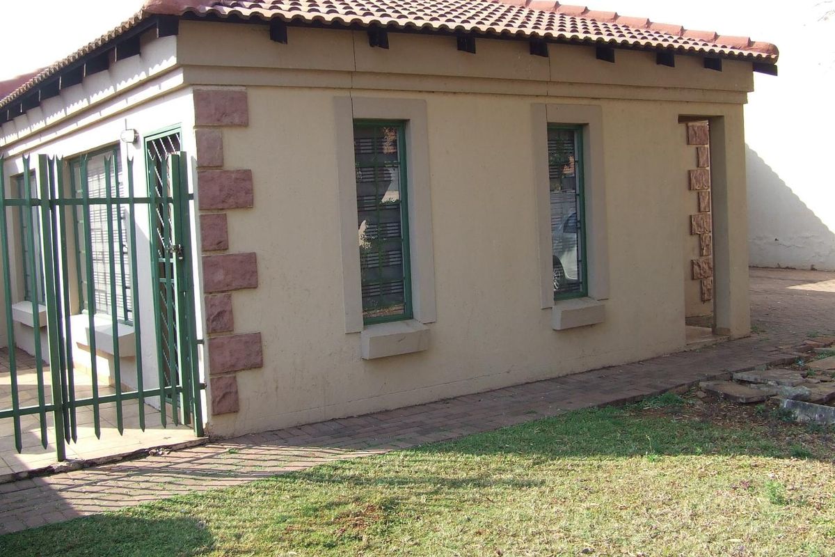 Rear view of the property featuring a tiled roof, security gates, and paved walkway with stone corner accents.