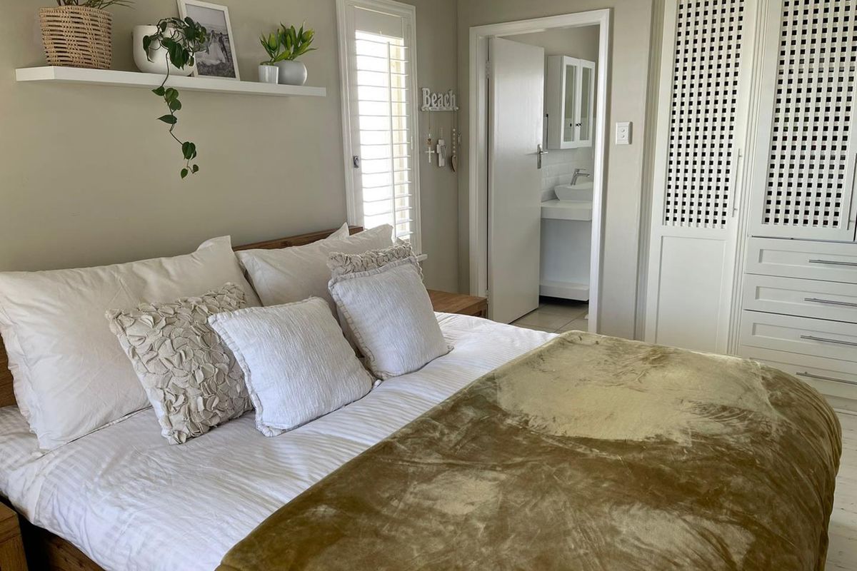 A well-maintained bedroom featuring built-in cabinetry with lattice detailing and an adjoining en-suite bathroom.