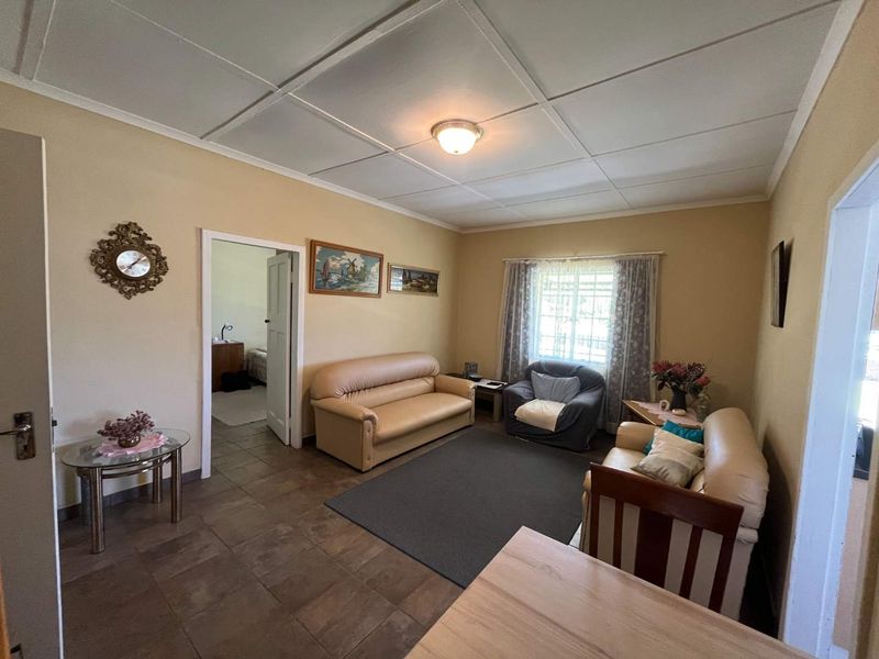 A living room featuring tiled flooring and a tiled ceiling, providing a functional space with access to an adjacent bedroom.