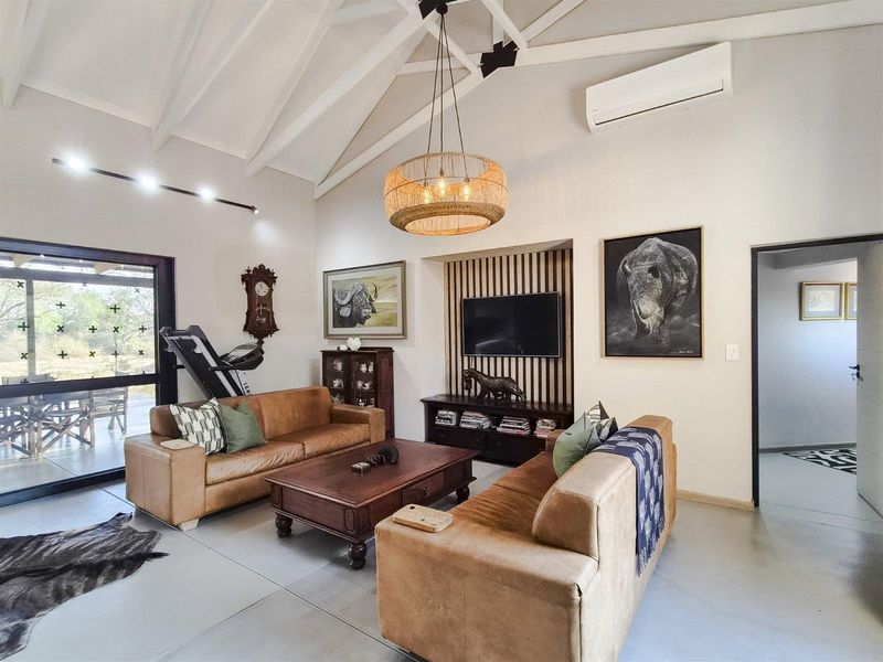 Spacious living room featuring a high vaulted ceiling with exposed rafters, polished concrete floors, and a modern timber slat feature wall.