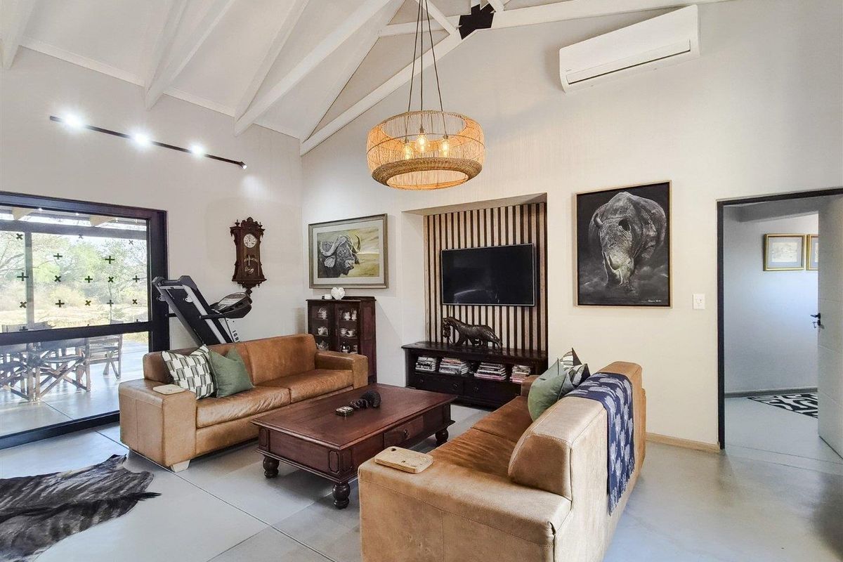 Spacious living room featuring a high vaulted ceiling with exposed rafters, polished concrete floors, and a modern timber slat feature wall.