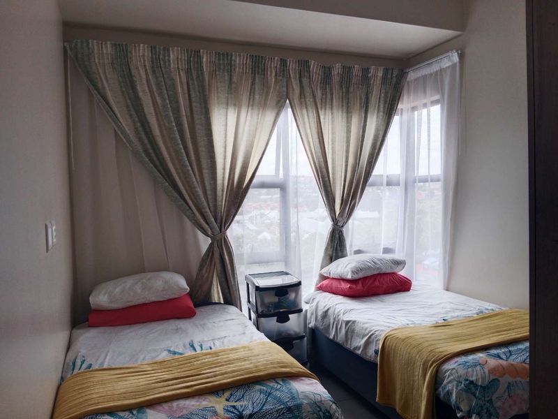 A bedroom featuring a large window with curtain tracks, providing natural light and an exterior view.