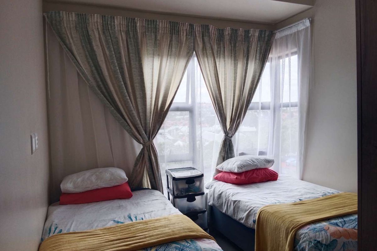 A bedroom featuring a large window with curtain tracks, providing natural light and an exterior view.