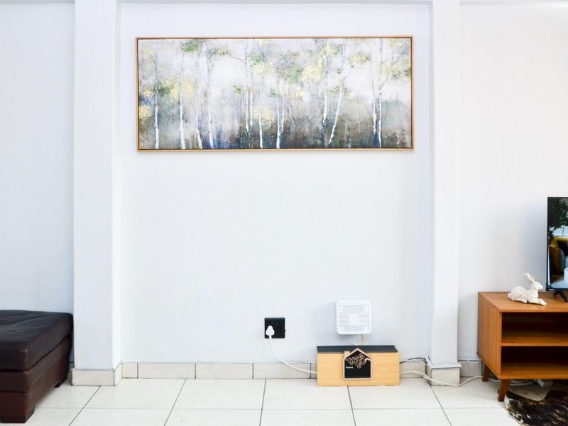 A clean living room area featuring neutral tiled flooring and a recessed wall section, providing a bright and well-maintained space.