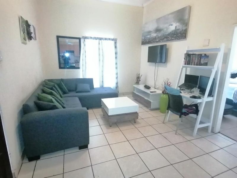 A living room area featuring ceramic floor tiles and a sliding glass door providing natural light.