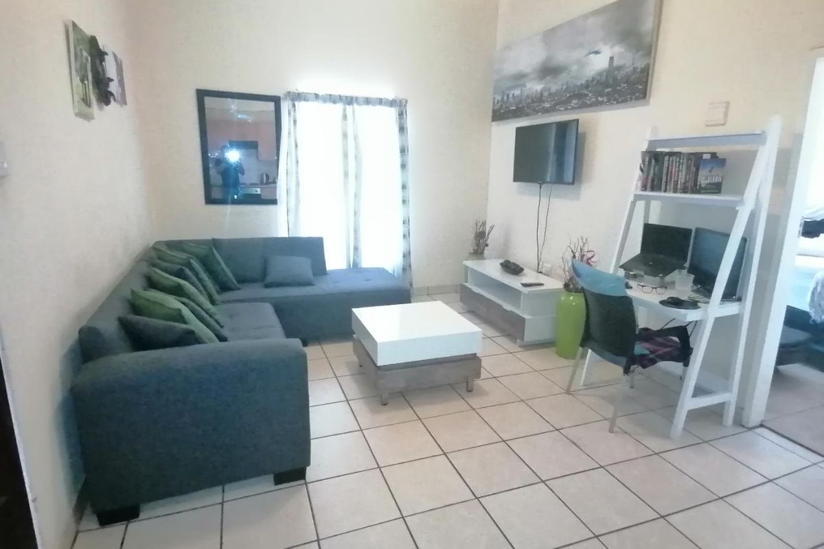A living room area featuring ceramic floor tiles and a sliding glass door providing natural light.