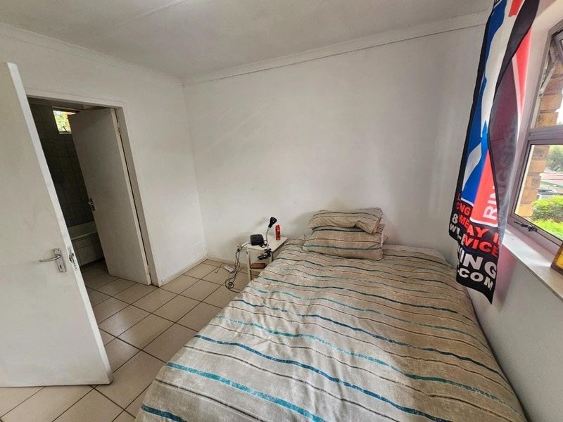 A functional bedroom featuring tiled flooring, coved ceilings, and an en-suite bathroom access point.
