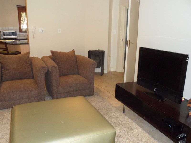 Open plan living area featuring tiled flooring, a freestanding fireplace, and an adjacent kitchen space.