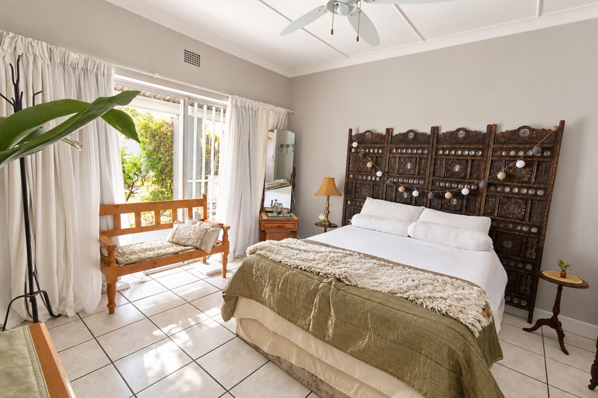 Spacious bedroom featuring tiled flooring, a ceiling fan, and large sliding glass doors providing direct access to the outdoor area.
