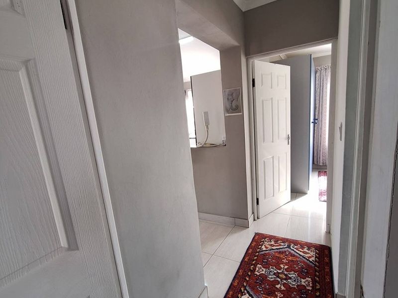 A functional hallway featuring tiled flooring, coved ceilings, and a loft access hatch, providing access to adjacent rooms within the home.