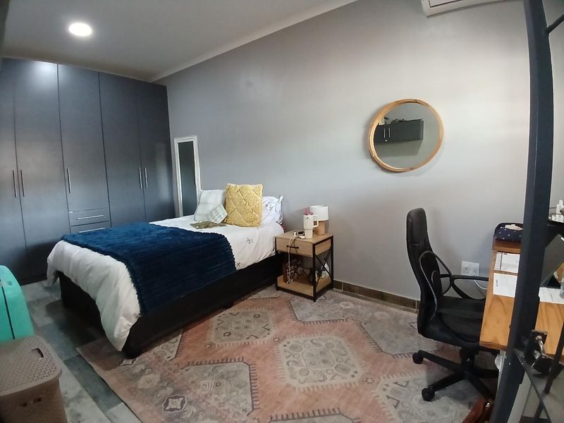A well-maintained bedroom featuring dark built-in cupboards, recessed lighting, and an integrated air conditioning unit, providing a functional and comfortable living space.
