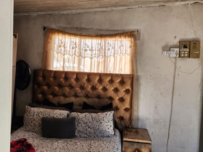 A bedroom featuring tiled flooring and a timber plank ceiling, currently requiring significant wall repairs and electrical maintenance to improve the overall condition.
