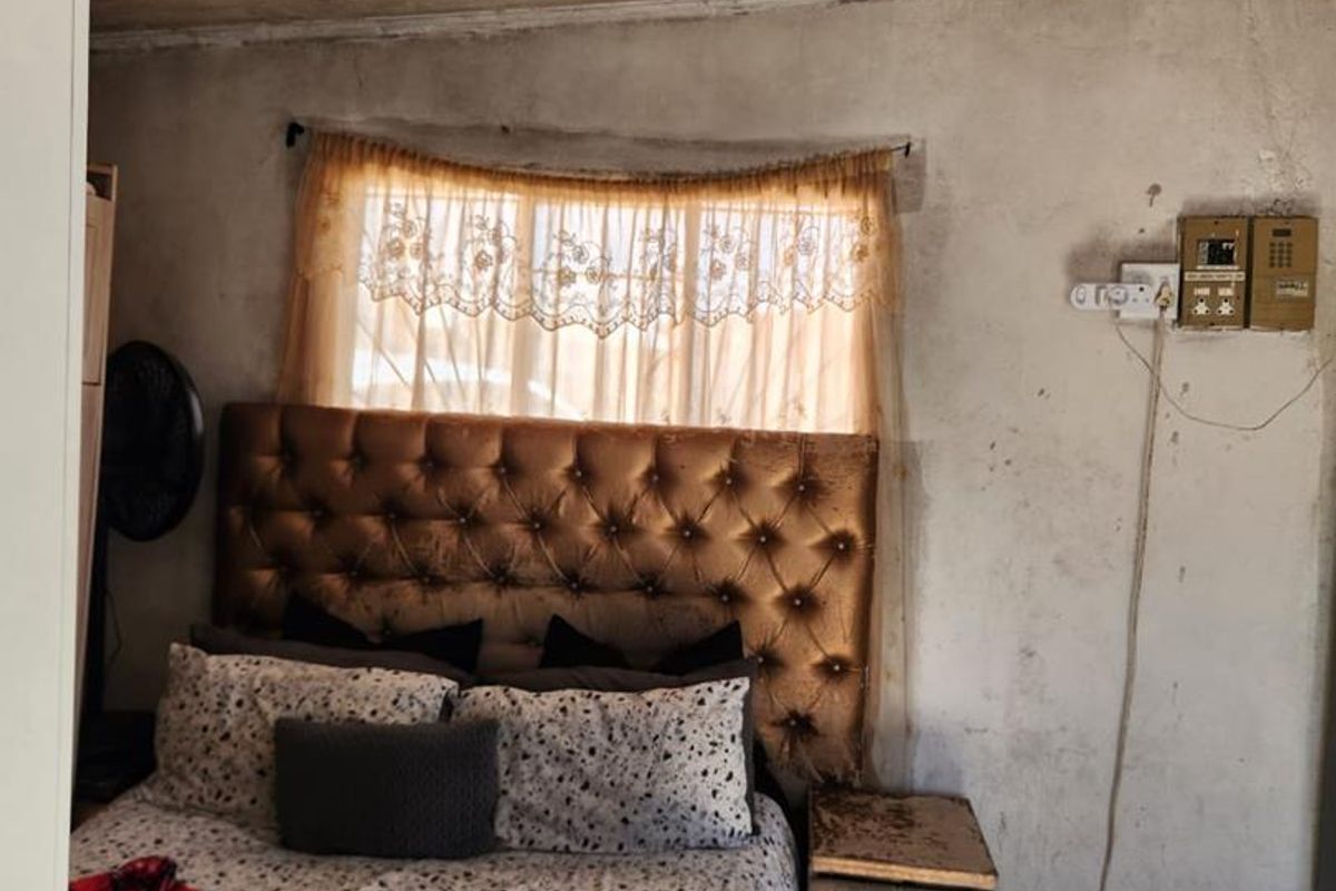 A bedroom featuring tiled flooring and a timber plank ceiling, currently requiring significant wall repairs and electrical maintenance to improve the overall condition.