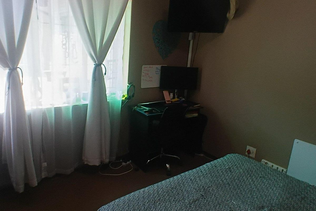 A bedroom featuring a window with curtains and standard electrical fixtures, providing a functional space for rest.