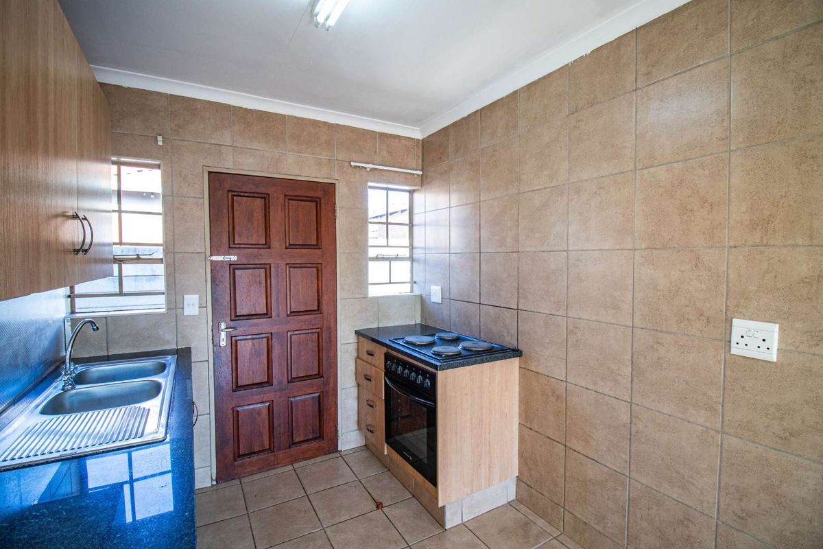 Functional kitchen featuring tiled walls, built-in cabinetry, a double sink, and a freestanding electric stove.