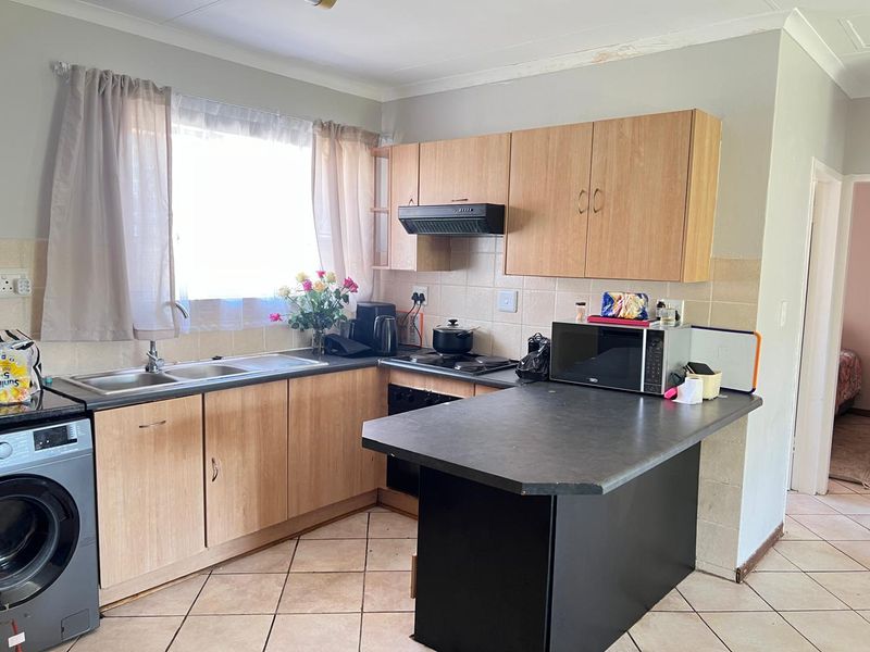 Functional kitchen featuring laminate cabinetry, dark countertops, tiled flooring, and a built-in hob with extractor fan.