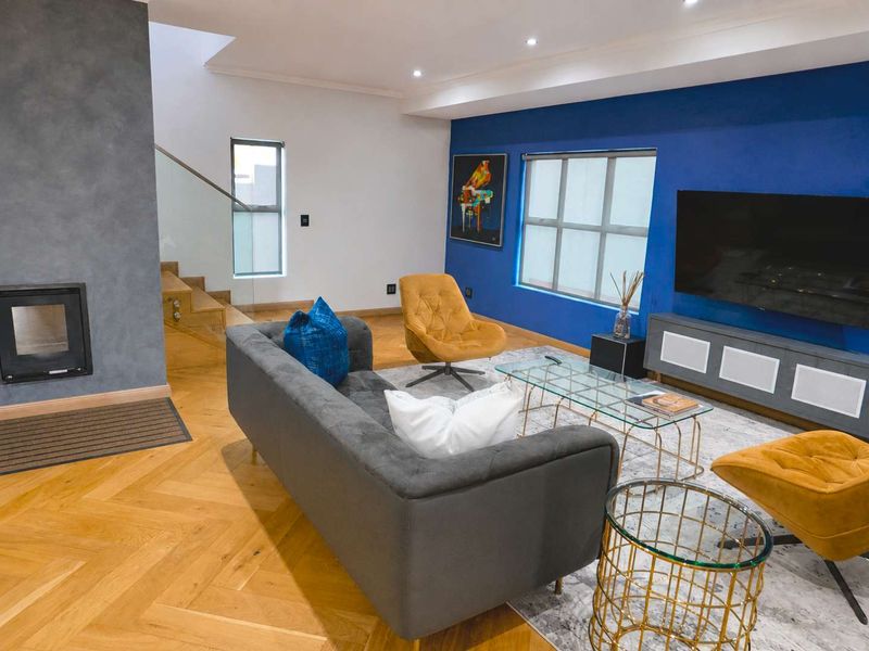 Modern living room featuring herringbone timber flooring, a sleek built-in fireplace, and a contemporary staircase with glass balustrades.