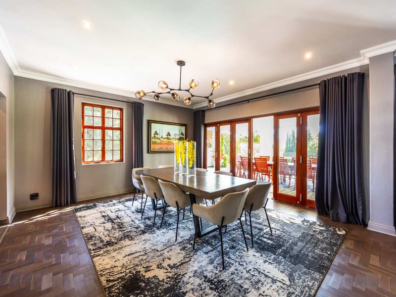 Elegant dining room featuring rich parquet flooring, crown molding, and large wooden sliding doors that open to an outdoor patio area.