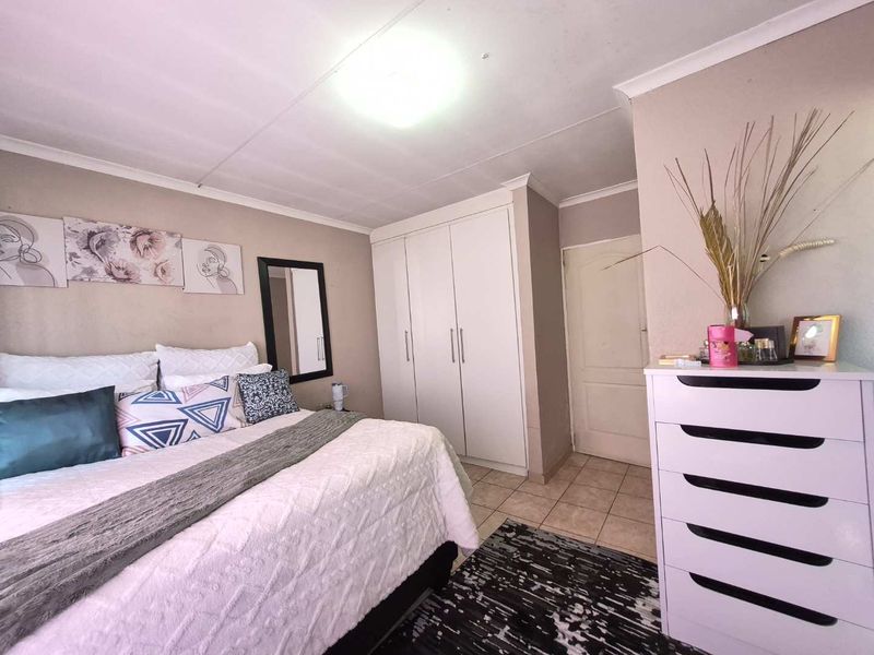 A bedroom featuring tiled flooring, a built-in wardrobe, and neutral wall finishes, providing a functional and well-maintained living space.