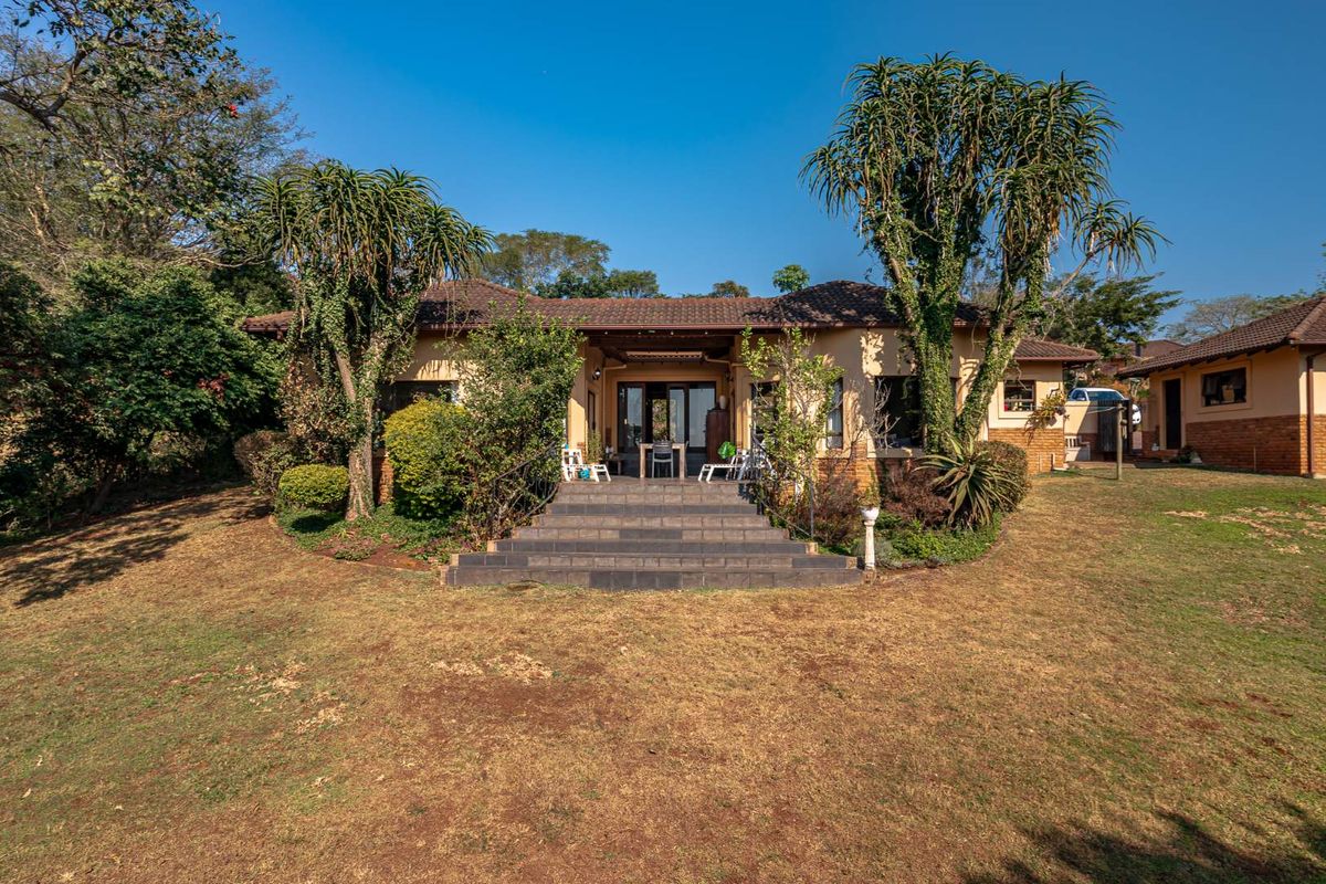 Rear view of the townhouse featuring a tiled patio with concrete stairs, wrought iron railings, and a spacious garden area.