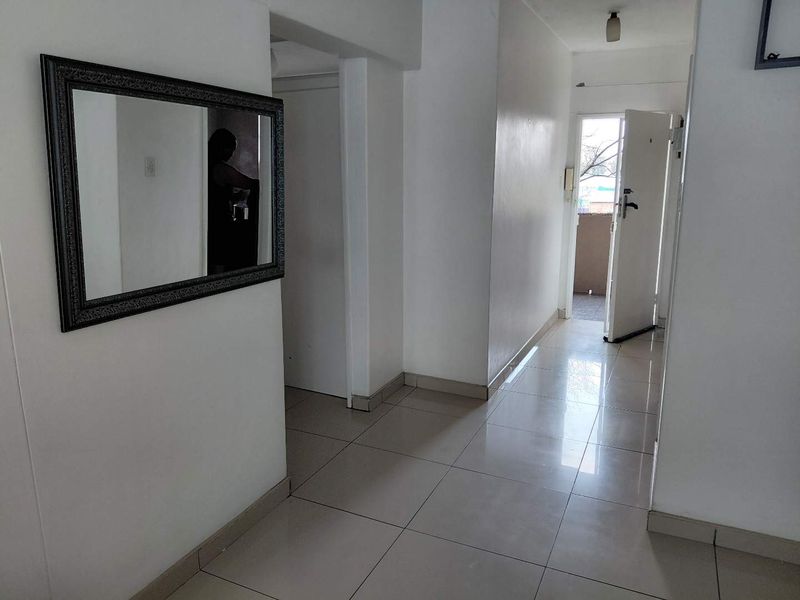 A bright, tiled hallway providing access to various rooms, featuring neutral walls and clean finishes throughout.