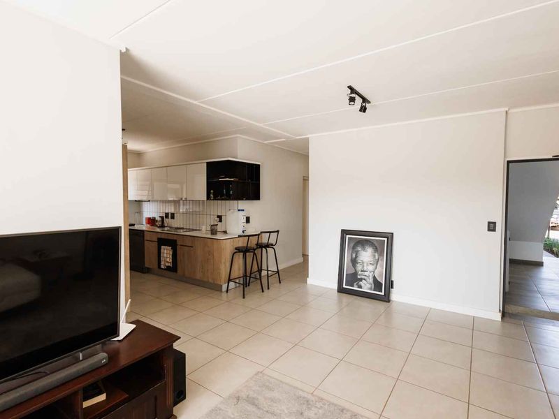 Open-plan living area featuring tiled flooring and a modern kitchen with built-in cabinetry, integrated oven, and hob.