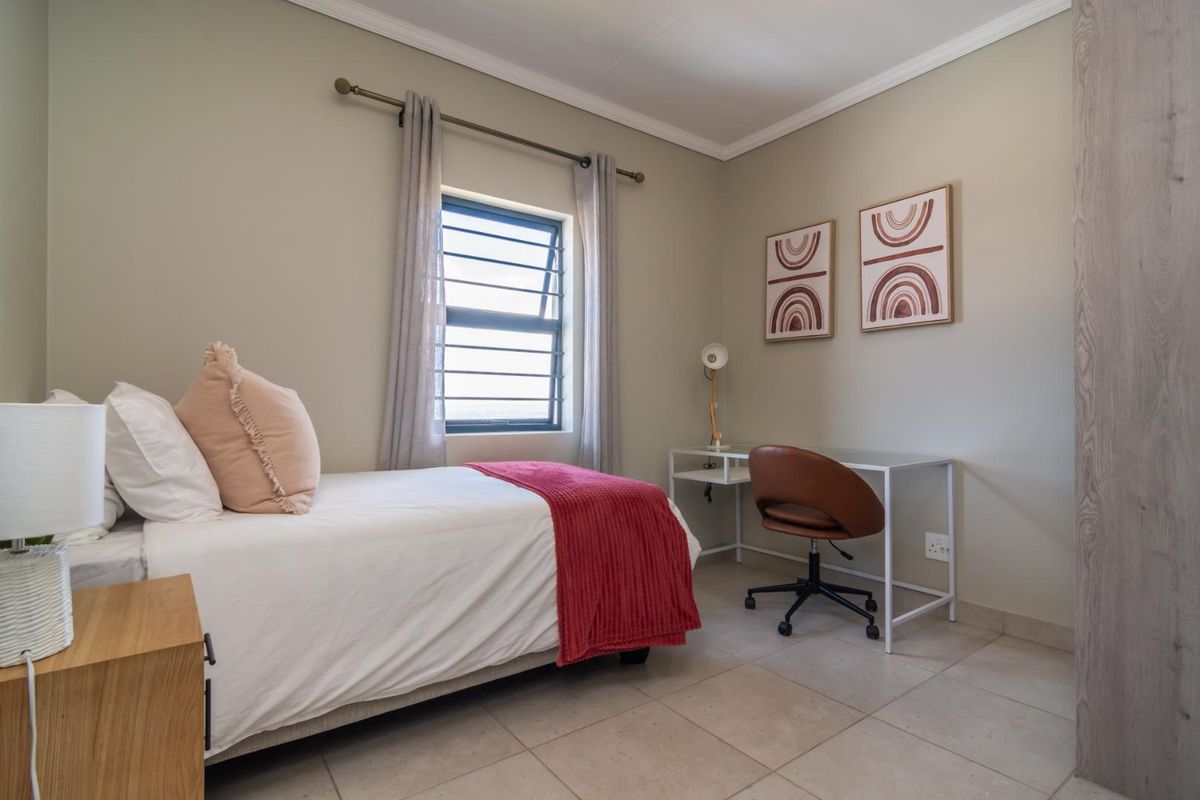 A well-maintained bedroom featuring neutral wall tones, tiled flooring, built-in storage, and a top-hung window providing natural light.