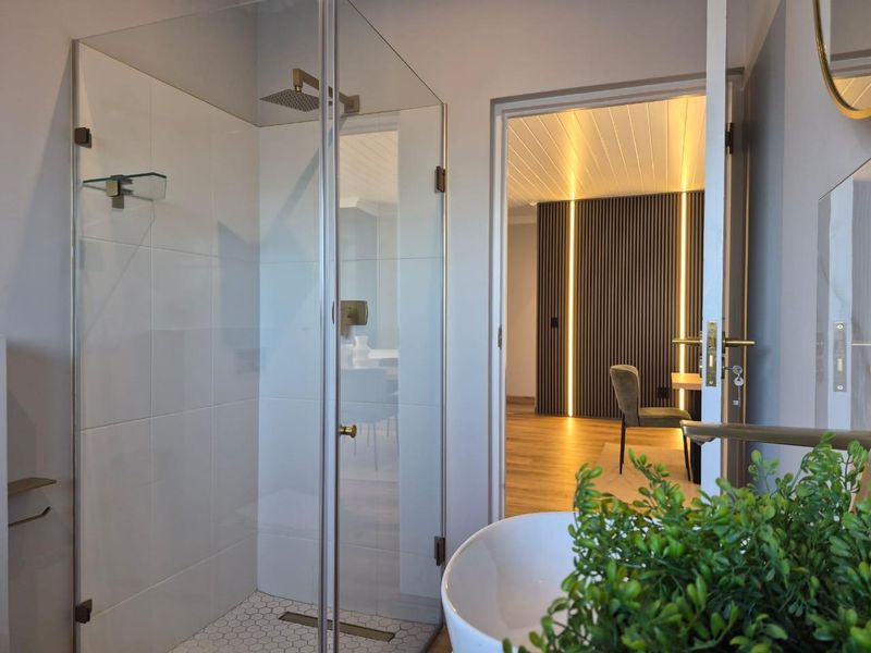 Modern bathroom featuring a glass-enclosed shower with a rain shower head, hexagonal floor tiling, and a contemporary vessel sink.