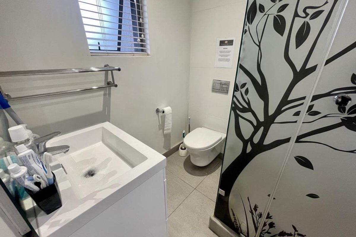 A modern bathroom featuring a wall-hung toilet, a contemporary vanity basin, and a decorative glass shower screen.