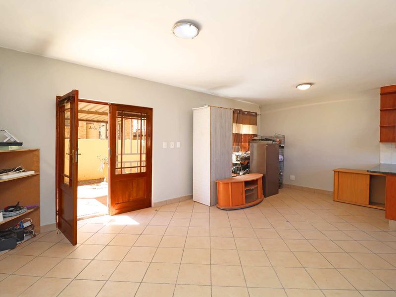 Open plan living area featuring tiled flooring, built-in kitchen cabinetry, and direct access to an outdoor patio space.