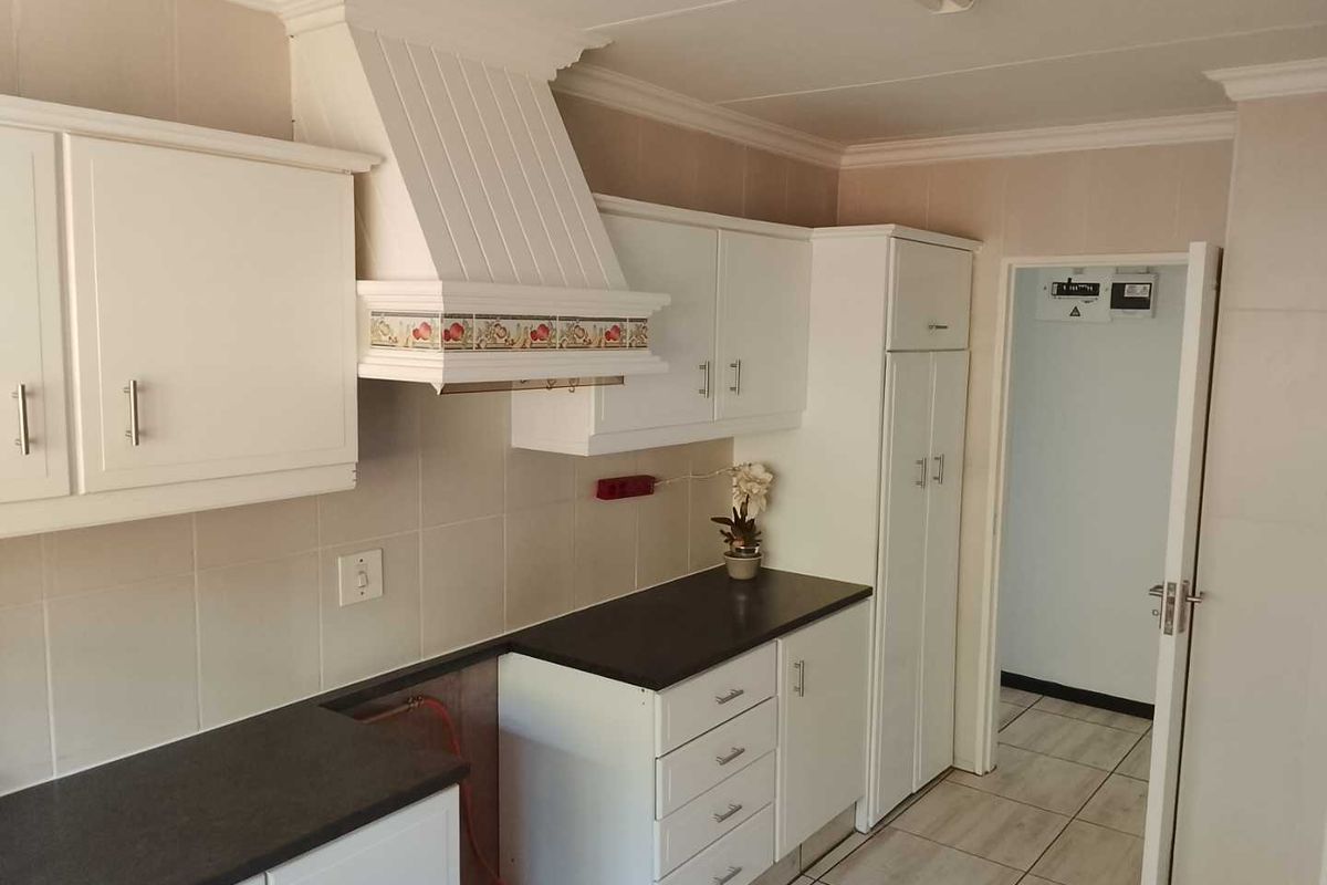 A functional kitchen featuring white cabinetry, dark countertops, tiled backsplash, and a built-in extractor fan, with space prepared for a stove installation.