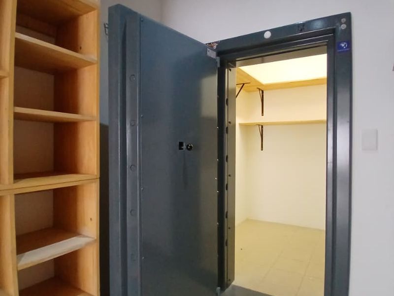 A secure utility room or walk-in safe featuring a heavy-duty steel vault door and built-in shelving units.