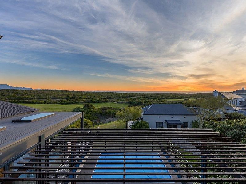 Elevated view overlooking a swimming pool with a timber pergola, featuring expansive landscape and sunset vistas.