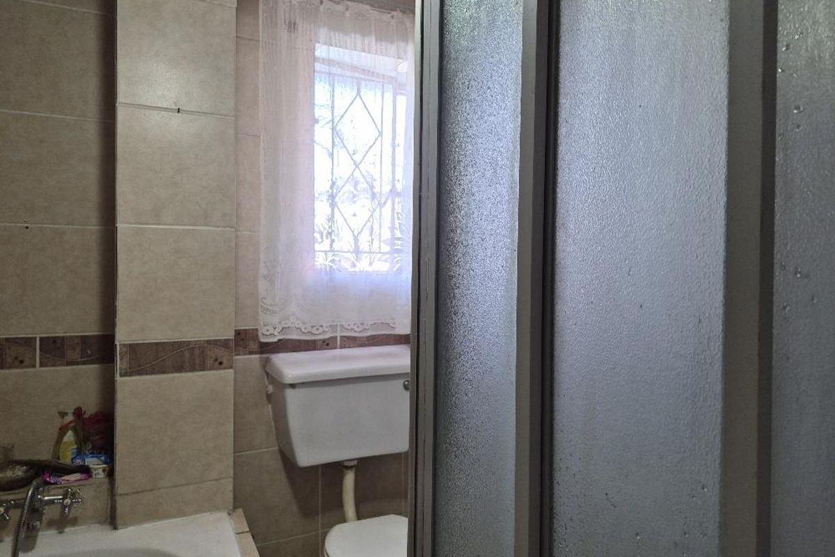 A functional bathroom featuring tiled walls, a standard toilet, and a shower enclosure with a glass door.