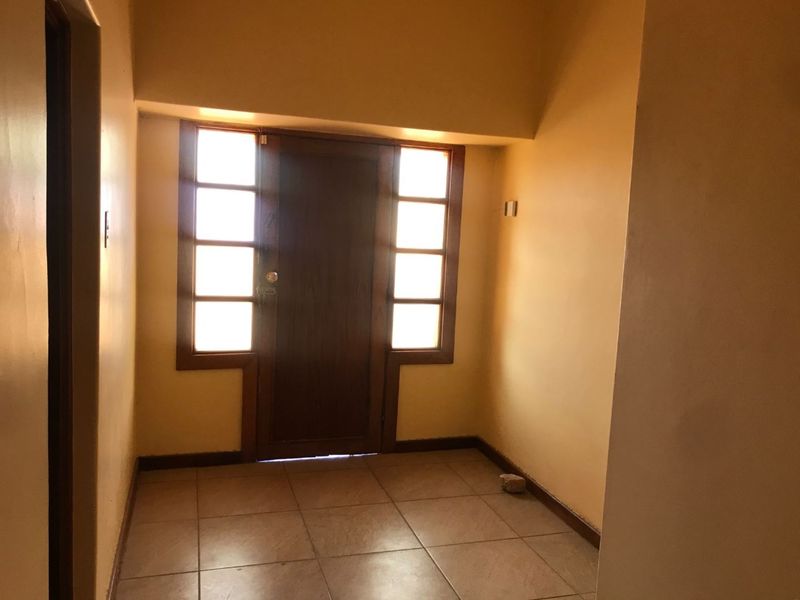 A vacant entrance foyer featuring a timber front door with sidelight windows and ceramic tiled flooring.
