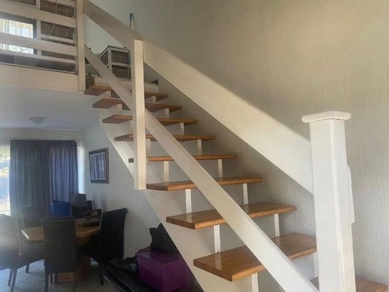 A living area featuring an open-tread wooden staircase leading to a mezzanine level, providing a unique architectural element to the space.