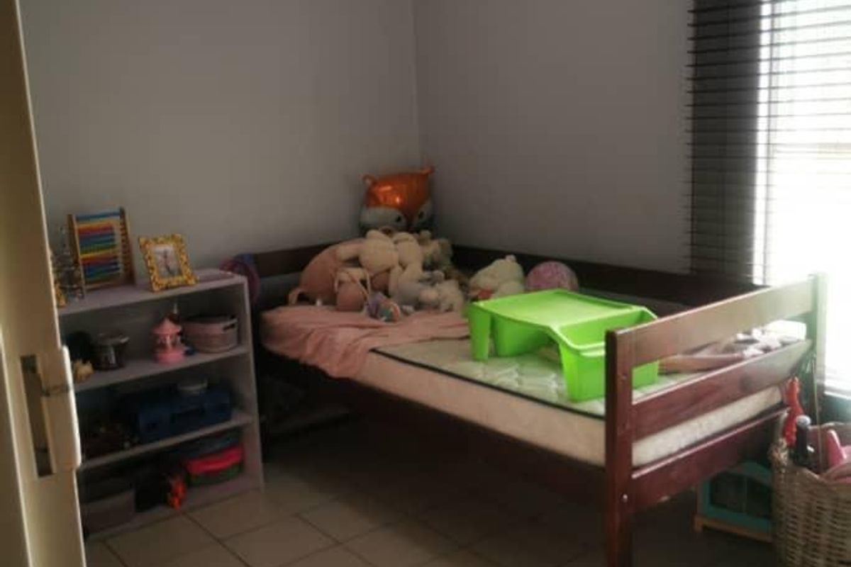 A functional bedroom featuring tiled flooring and a window fitted with horizontal blinds.