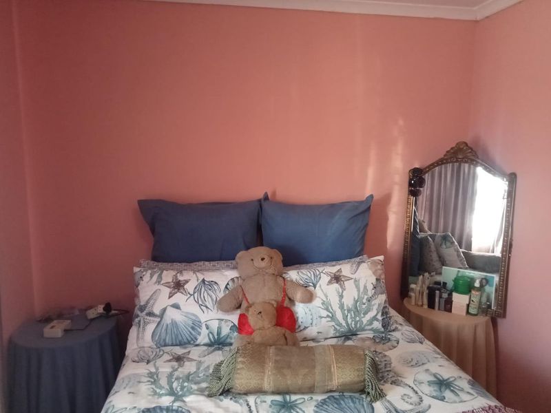 A bedroom featuring pink painted walls and a central bed placement.